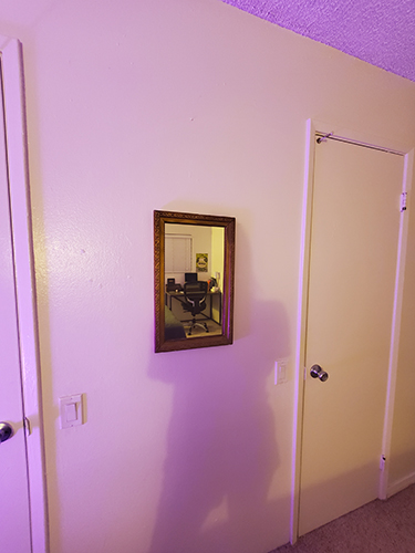 A desk reflected in a mirror on a wall.