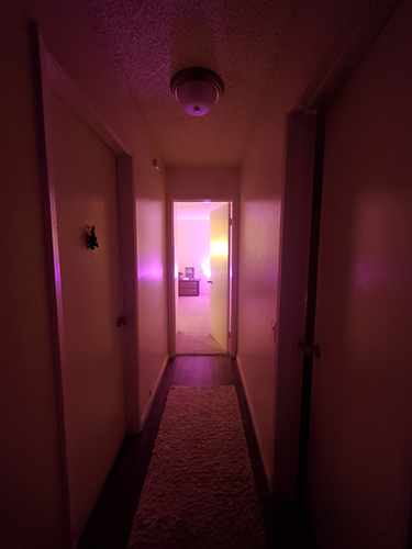 An illuminated room at the end of a dark hallway.