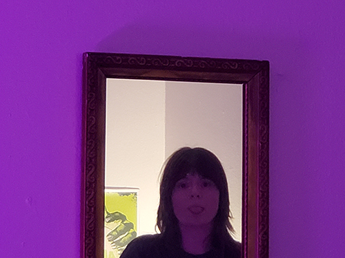 A girl sticking her tounge out reflected in a mirror.